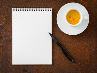Obraz na płótnie Canvas white empty blank sheet of notebook with a spiral, pencil and cup of coffee on rusted old iron table, top view.