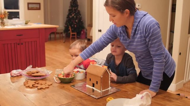 A family decorates a small ginger bread house for christmas