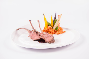 Lamb chops, braised lentils with mint, roast vegetables and rosemary sauce on a white background