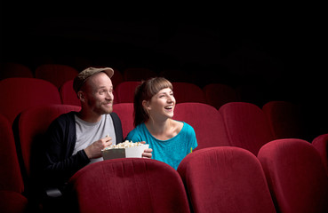 Fototapeta premium Young couple sitting at red movie theatre