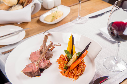 Lamb chops, braised lentils with mint, roast vegetables and rosemary sauce served in a restaurant
