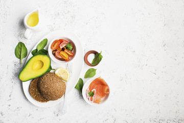 Healthy breakfast: cereal rolls with salmon, cherry tomatoes, spinach, avocado. blueberry on a light background. Top view. Copy space.