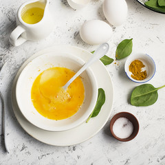 Ingredients for scrambled eggs with spinach and turmeric on the background. Top view. Copy space.