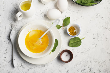 Ingredients for scrambled eggs with spinach and turmeric on the background. Top view. Copy space.