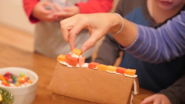 Family decorates small ginger bread house for christmas