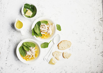 Fresh homemade chicken soup broth with corn, spinach, boiled breast on a light background. Top view. Copy space.