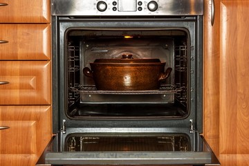 Electric domestic oven and ceramic pot. Baking dishes for meat. Preparing food in the oven.