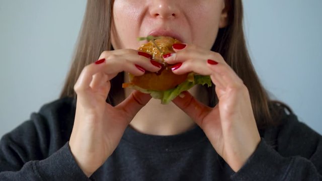 Woman eats juicy hamburger