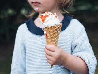 Kleines Kind isst Eis und hat einen verschmierten Mund