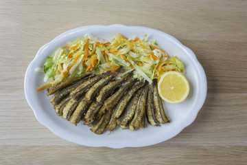 Anchovy with salad and a lemon in a white plate