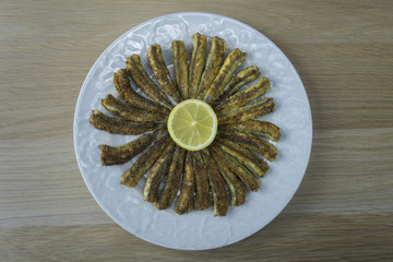 Anchovies rounded in a white plate with a lemon disk