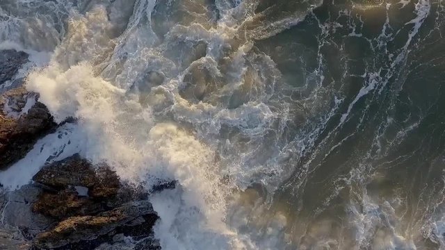 Ariel view of waves rolling onto the rocks at Bracelet Bay on the Gower peninsula in Swansea, South Wales, UK
