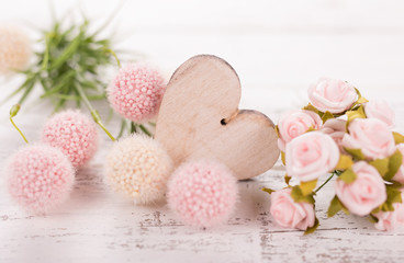 Flowers composition for Valentine's, Mother's or Women's Day. Pink flowers with wooden hearth on old white wooden background.