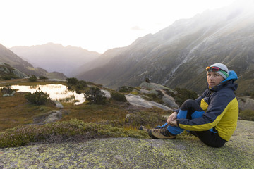 Naklejka na ściany i meble Young alpinist enjoys the sunrise after a strict mountain tour