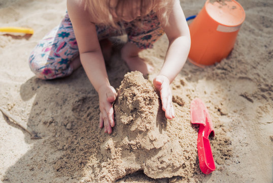 Kleines Mädchen spielt im Sand und baut eine Sandburg
