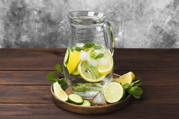 Detox drink with cucumber, lemon and mint in glass jug on a wooden background
