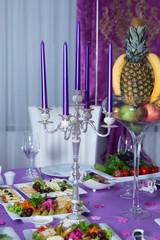 Candles and dishes on the table . Romantic tablet . Table served with tasty dishes and decorated with candles for a wedding celebration dinner in luxury restaurant