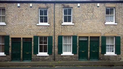 street with a row of typical british old terraced houses with green doors and window shutters in durham england