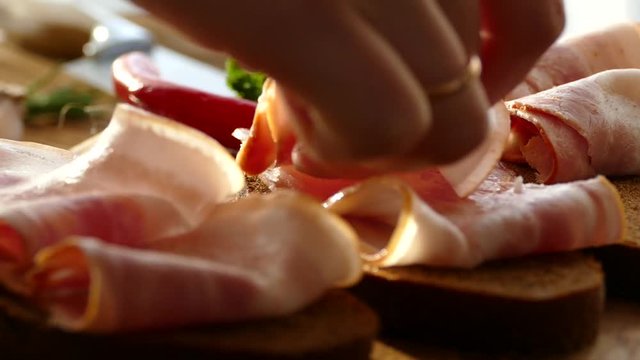 Sandwich with bacon and cheese. Black bread with bacon and spices. Cheese with holes on the plate. Thinly sliced pork meat