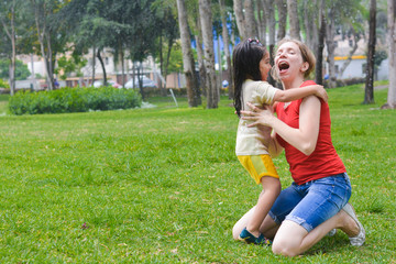 Fototapeta premium Happy biracial family in the summer park - caucasian mom with her little latin daughter having fun.