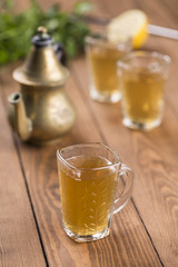 arabic mint and lemon tea glass with teapot on wooden table