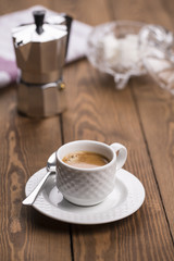white coffee cup with vintage coffee maker and sugar on wooden table