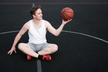 Fototapeta premium attractive man holding basketball and looking at ball
