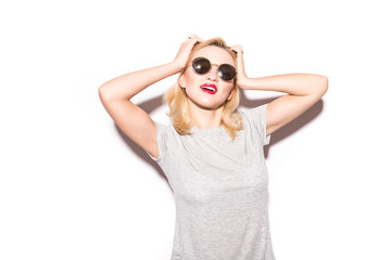 Stylish fashion sexy blonde bad crazy girl in a black t-shirt and rock sunglasses scream holding her head. Dangerous rocky emotional woman on White background