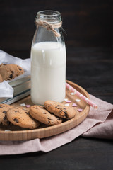 Chocolate chip cookies and a bottle of milk on a wooden table de