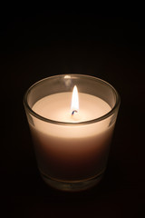 Obraz na płótnie Canvas Burning candle in glass at night.