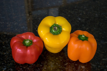 One red, yellow and orange pepper side by side.
