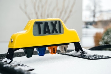 Side view of yellow Taxi sign covered with snow on a cold winter day
