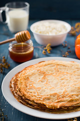 Fresh pancakes with honey, maple syrup, cottage cheese and tangerines. Wooden background. Top view