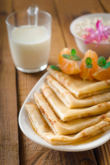 Fresh pancakes with honey, maple syrup, cottage cheese and tangerines. Wooden background. Top view