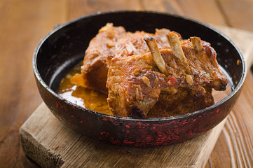 Baked pork ribs in a frying pan. Wooden rustic background. Top view. Selective focus