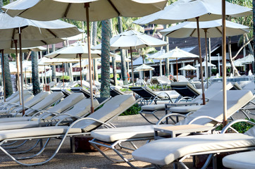 Obraz premium The sun beds and umbrella at a swimming pool in resort.