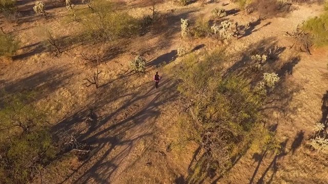 Aerial orbit of a woman hiking on a desert trail