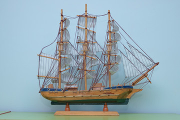 Wooden small ship isolated on white background . Sailing ship model in souvenir shop, closeup. Handmade sailboat miniature in gift market. 