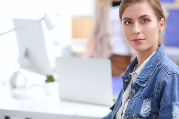 Two young woman sitting near desk with instruments, plan and laptop.