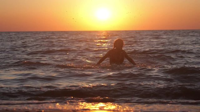 Woman playing with water in the sea at amazing sunset. Free during holidays vacation travel. slow motion. 1920x1080