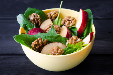 Spinach salad with nuts and apples served on table