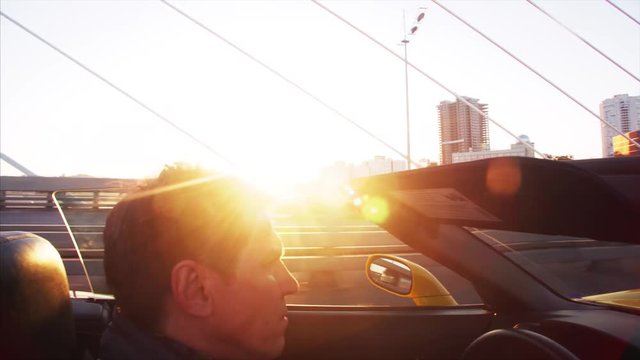 Middle aged man is driving his luxurious cabriolet moving along the Golden Bridge across the Golden Horn harbour in the morning. Vladivostok, Russia