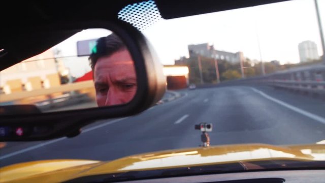 Road from moving cabriolet , view of middle aged driver's face in the mirror. Car is moving through the dark tunnel. Vladivostok, Russia