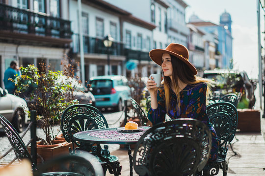 Smiling woman with cup in outside cafe