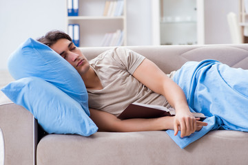 Young student man preparing for college exams in bed with book