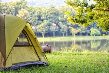 Camping green tent in forest near lake - obrazy, fototapety, plakaty