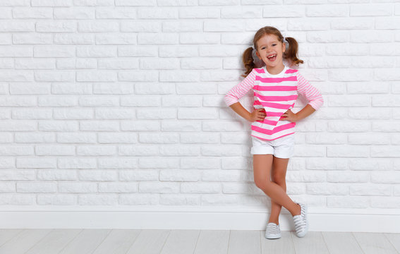 happy child girl near an empty brick wall