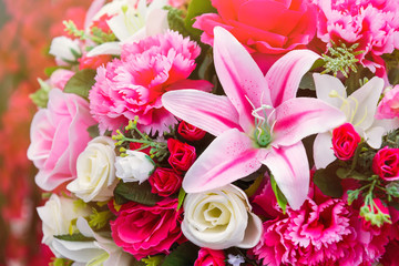 Close up to colorful plastic pink lilly flowers with roses and little flowers in a bouquet.