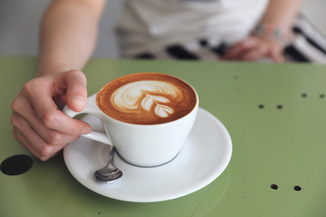 Cappuccino coffee with young woman hand