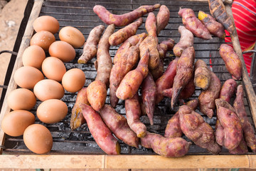 Sweet yam, egg, toast on grill grate traditional cooking (Broiled yam on charcoal broiler) in Thailand.